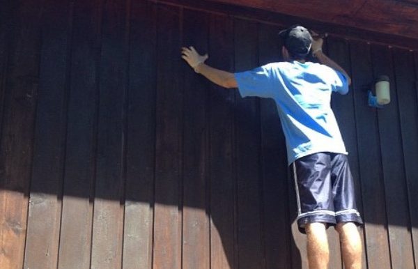 Man staining the side of a house
