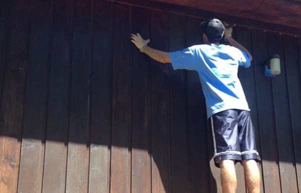 Man staining the side of a house